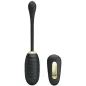 Preview: Black, elongated massage device with remote control, gold accents, on a white background.