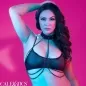 Preview: Frau in schwarzem Dessous vor pinkem Hintergrund, Hand im Haar, mit Ketten-Details.