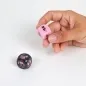 Preview: A hand holds a pink cube with symbols, next to it a black cube on a table.
