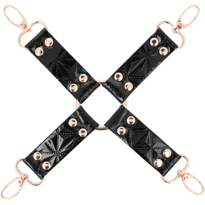 Schwarzes Lederkreuz mit goldenen Nieten und Ringen, vier Haken an den Enden.