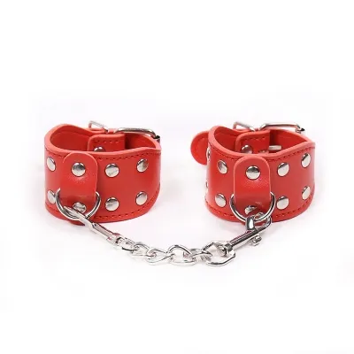 Red leather handcuffs with silver studs and chain on a white background.