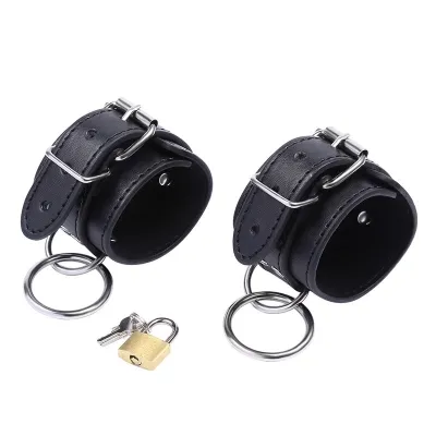 Two black leather restraints with metal buckles and rings, next to them a padlock with keys.