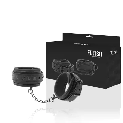 Schwarze Handfesseln mit Kette vor Verpackung mit der Aufschrift "Fetish Submissive".