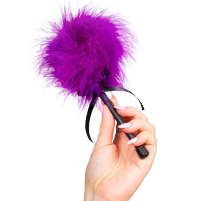 Hand holding purple feather duster with black handle.