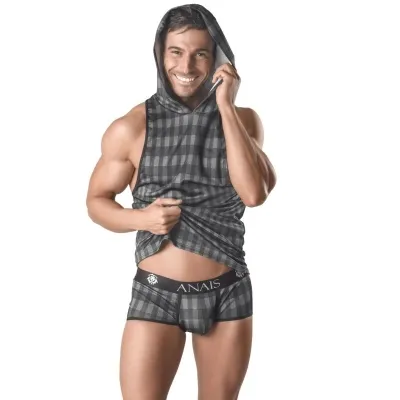 Man in a checkered hoodie and boxer shorts, smiling, against a white background.