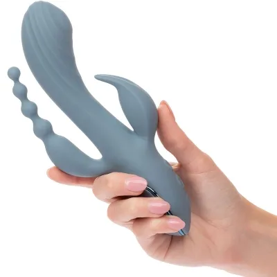 Hand hält blauen Vibrator mit mehreren Anhängen vor weißem Hintergrund.
