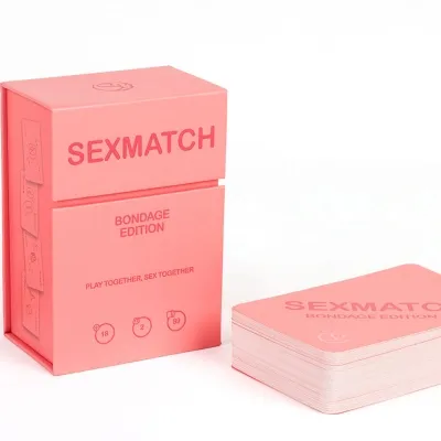 Rosa Kartenspielbox mit der Aufschrift "Sexmatch Bondage Edition" und einem Stapel Karten daneben.