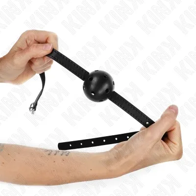 Two hands hold a black ball gag with holes and an adjustable strap against a white background.