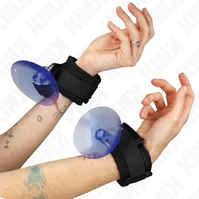 Two hands with black handcuffs and blue suction cups, tattooed, against a white background.