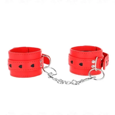 Rote Handfesseln mit schwarzen Herzmotiven, verbunden durch eine silberne Kette.