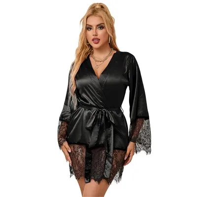 Frau in schwarzem Satin-Kimono mit Spitzenärmeln und Gürtel, blondes Haar, trägt Schmuck.