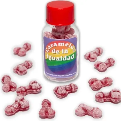 Bottle containing red, penis-shaped candies, labeled "Caramelos de la Igualdad", surrounded by scattered candies.