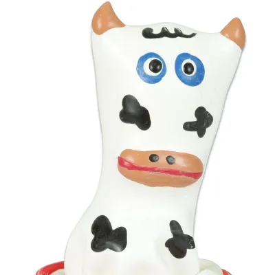 Toy cow with blue eyes, black spots and orange ears on a white background.