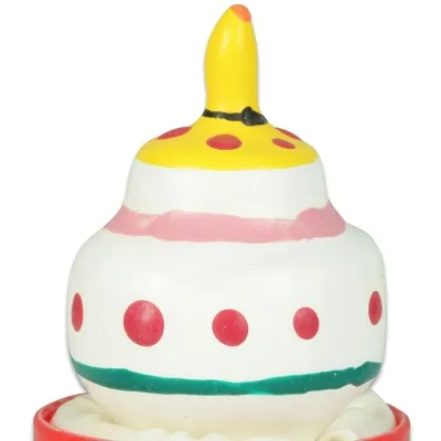Bunte, gestufte Kerze in Form einer Torte mit gelber Spitze und roten Punkten auf weißem Hintergrund.