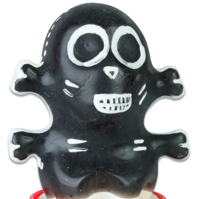 Schwarzes, cartoonartiges Gummispielzeug mit weißen Augen und Zähnen, das wie ein Skelett aussieht.