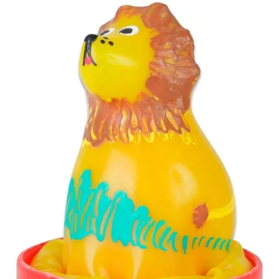 Gelbe Löwenfigur mit brauner Mähne und blauen Verzierungen, sitzt auf einem roten Sockel.
