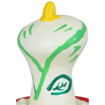 Weiße Gummifigur mit grünen Linien und gelber Spitze, die an einen Vogel erinnert.