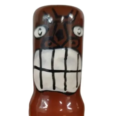 Keramikfigur mit grimmigem Gesichtsausdruck, großen Augen und breitem, gezacktem Mund.