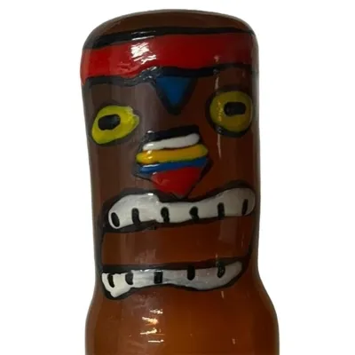 Bottle with a colorful, tribal face, red and yellow details, wide mouth and large eyes.