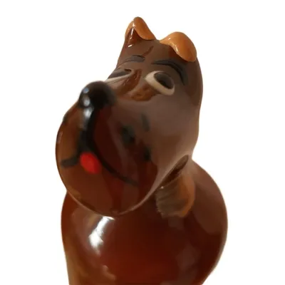 Brown glass figurine of a dog with a tilted head and closed eyes, on a white background.