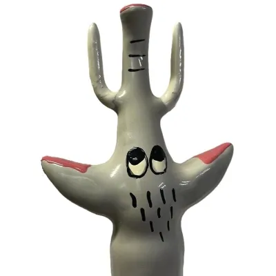 Ceramic figure of a stylized cactus with a face and red tips on a white background.