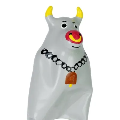 Grey cow figurine with yellow horns, red muzzle and bell around its neck.