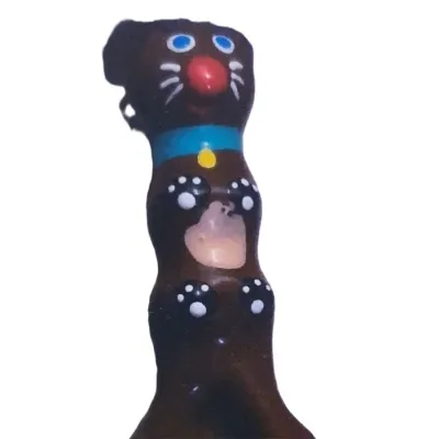 Schokoladenfigur in Tierform mit blauen Augen, roter Nase und blauer Halskette auf weißem Hintergrund.