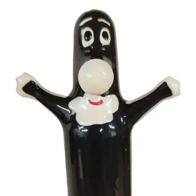Schwarze Cartoonfigur mit großen Augen, weißem Gesicht und erhobenen Armen, trägt ein weißes Lätzchen mit rotem Lächeln.