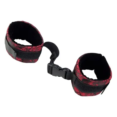 Black and red handcuffs with buckle closure, connected by a short strap.