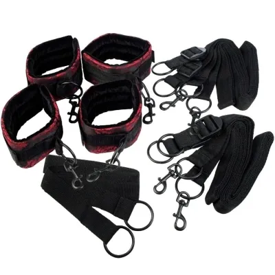 Black and red handcuffs and leg irons with buckles and straps on a white background.