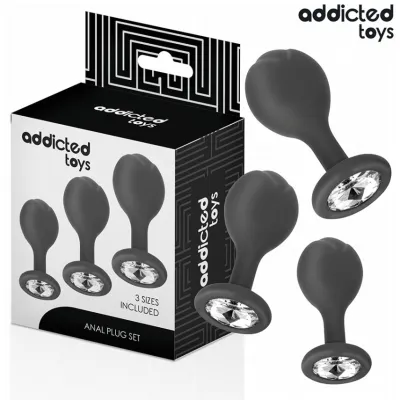 Black anal plug set in three sizes, decorated with crystals, next to the packaging of "Addicted Toys".