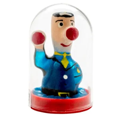 Spielzeugfigur in Uniform mit roter Nase und Ball, unter einer durchsichtigen Kuppel.