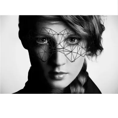 Woman with geometric mask, black and white, serious face, hair braided to the side.