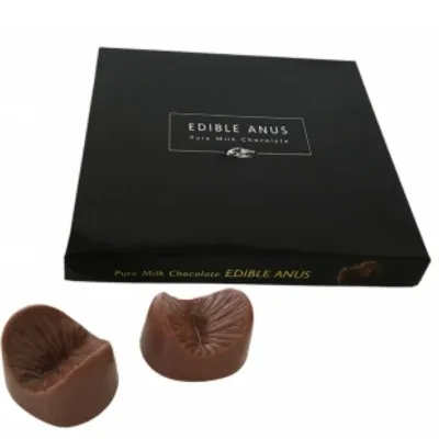 A box labeled "Edible Anus" with two chocolate-shaped anus-shaped pralines in front of it.