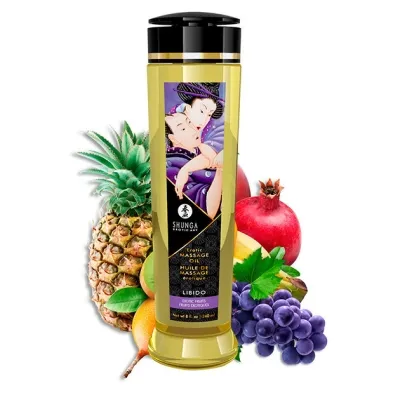 Bottle of Shunga massage oil with exotic fruits such as pineapple, pomegranate and grapes in the background.