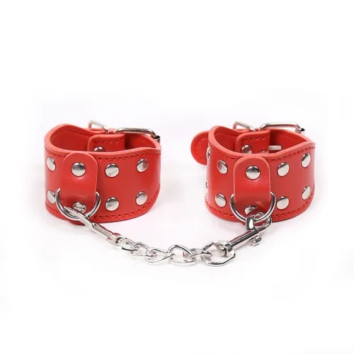 Red leather handcuffs with silver studs and chain on a white background.