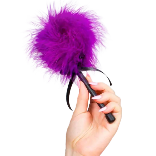 Hand holding purple feather duster with black handle.