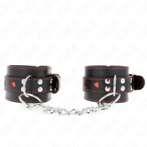 Schwarze Lederhandschellen mit roten Nähten und Herzdetails, verbunden durch eine Metallkette.