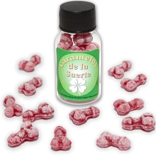 Glass bottle containing red, penis-shaped candies, surrounded by other candies on a white background.