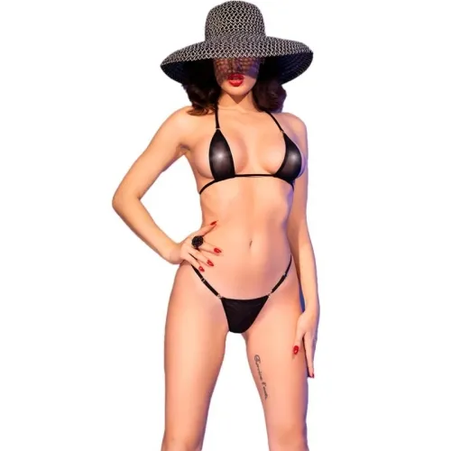 Person in schwarzem Bikini und großem Hut, posiert mit einer Hand auf der Hüfte vor weißem Hintergrund.