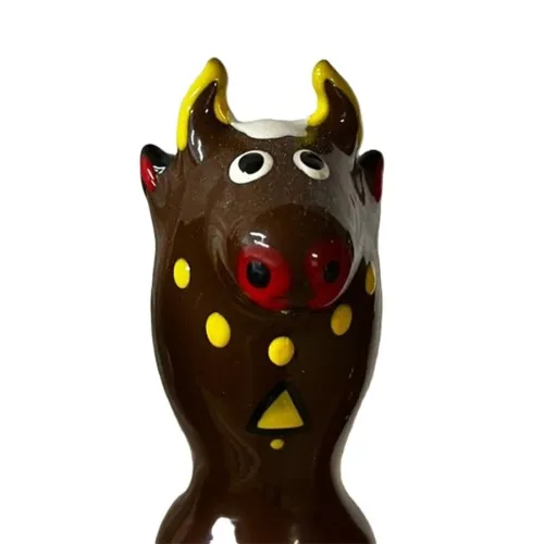 Ceramic figure of a brown bull with yellow horns and spots, red snout and large eyes.
