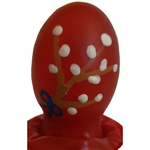 Rotes Osterei mit weißem Punktmuster und blauer Schleife, aufrecht stehend.