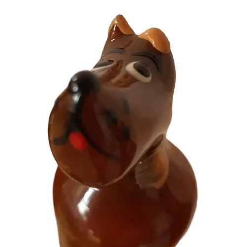 Brown glass figurine of a dog with a tilted head and closed eyes, on a white background.