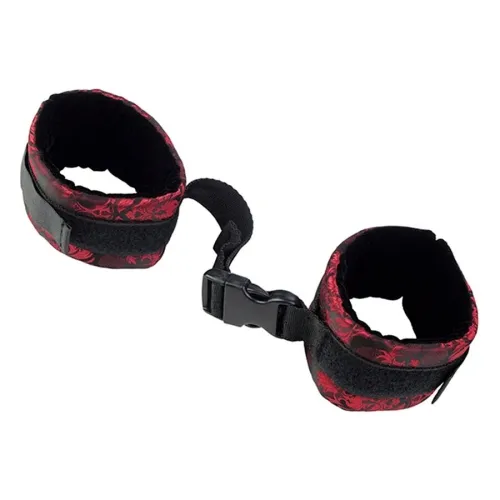 Black and red handcuffs with buckle closure, connected by a short strap.