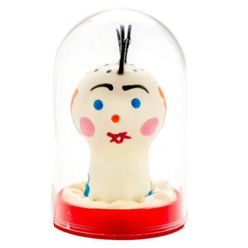 Spielzeugfigur mit Gesicht, bunten Details und schwarzem Haar, in einer durchsichtigen Kuppel auf rotem Sockel.