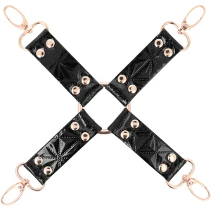 Schwarzes Lederkreuz mit goldenen Nieten und Ringen, vier Haken an den Enden.