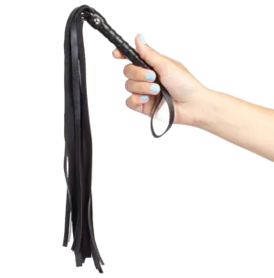 Hand hält eine schwarze Lederpeitsche mit mehreren Riemen.