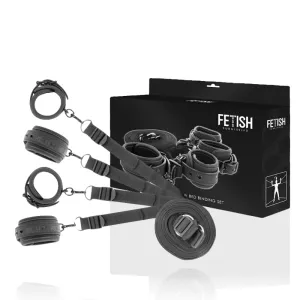 Schwarzes Bondage-Set mit Fesseln und Gurten vor einer Verpackung mit der Aufschrift 