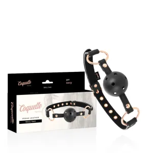 Schwarzer Ballknebel aus veganem Leder mit Verpackung, goldene Details, Marke Coquette Fantasy.