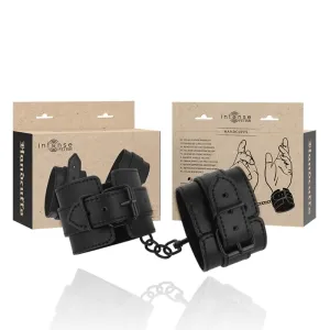 Schwarze vegane Lederhandschellen mit Verpackung im Hintergrund, illustriert mit Händen.
